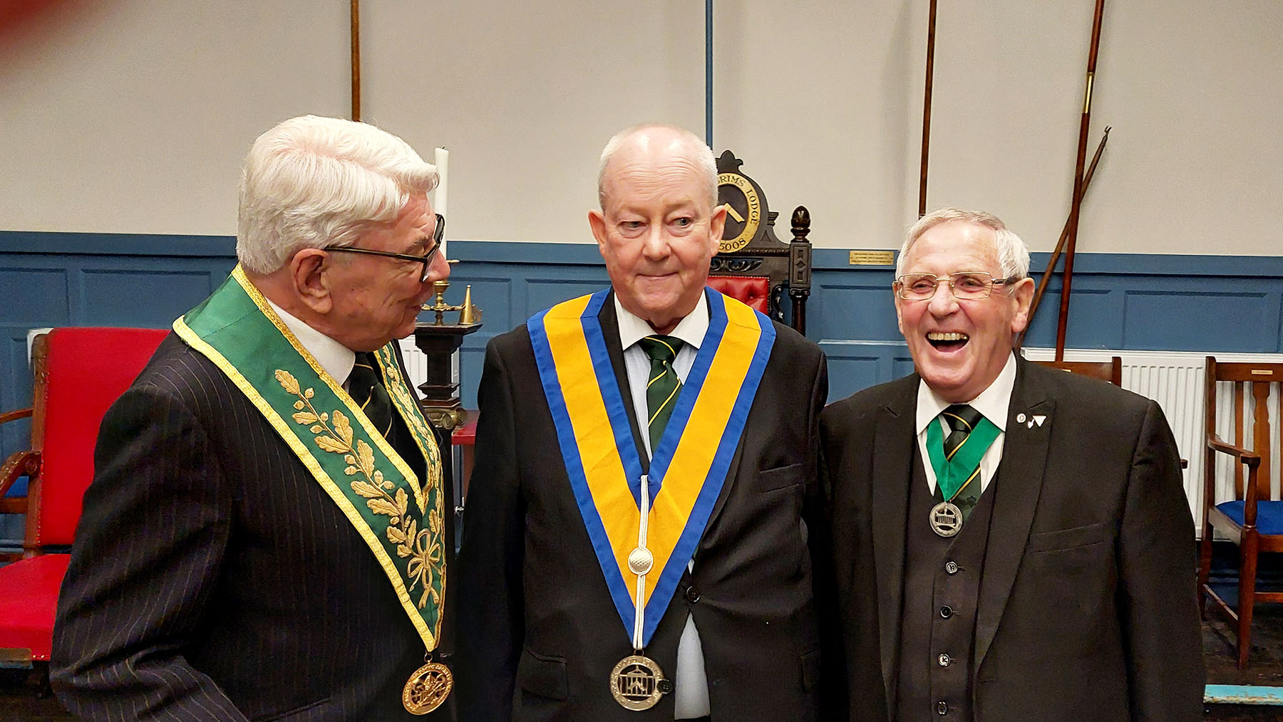 W. Bro Roland Wade enjoys a joke with the Installing Master W.Bro Ron Jakes whilst the newly installed  Master W. Bro Nigel Cash wonders what is going on